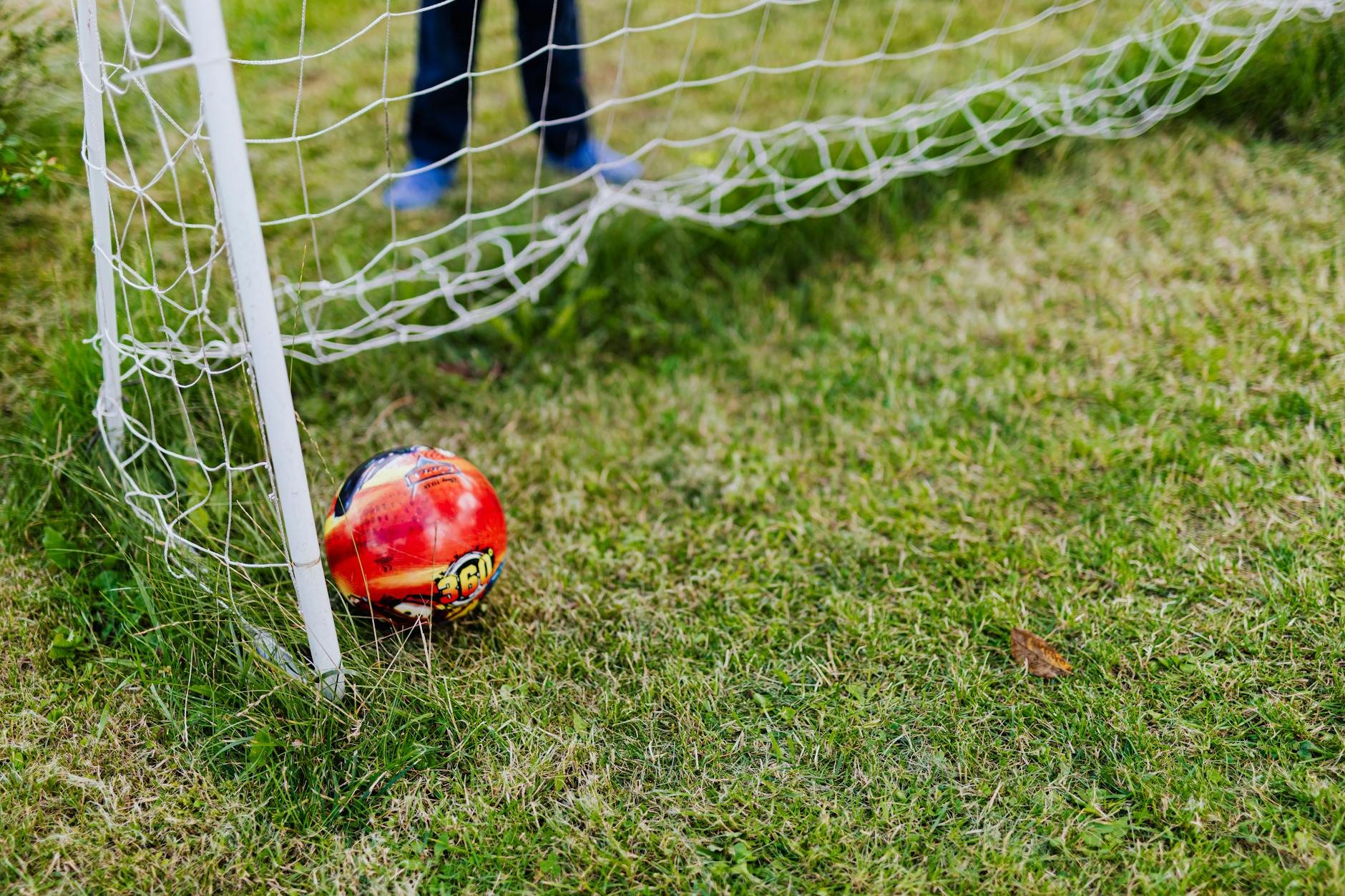 A colorful soccer ball resting in a net on a vibrant green field, signifying victory.
