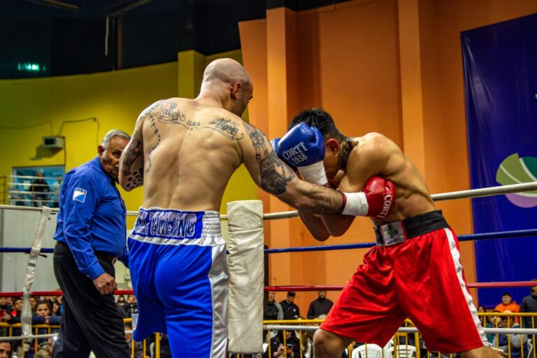 Two male boxers in gloves fighting in a boxing ring.