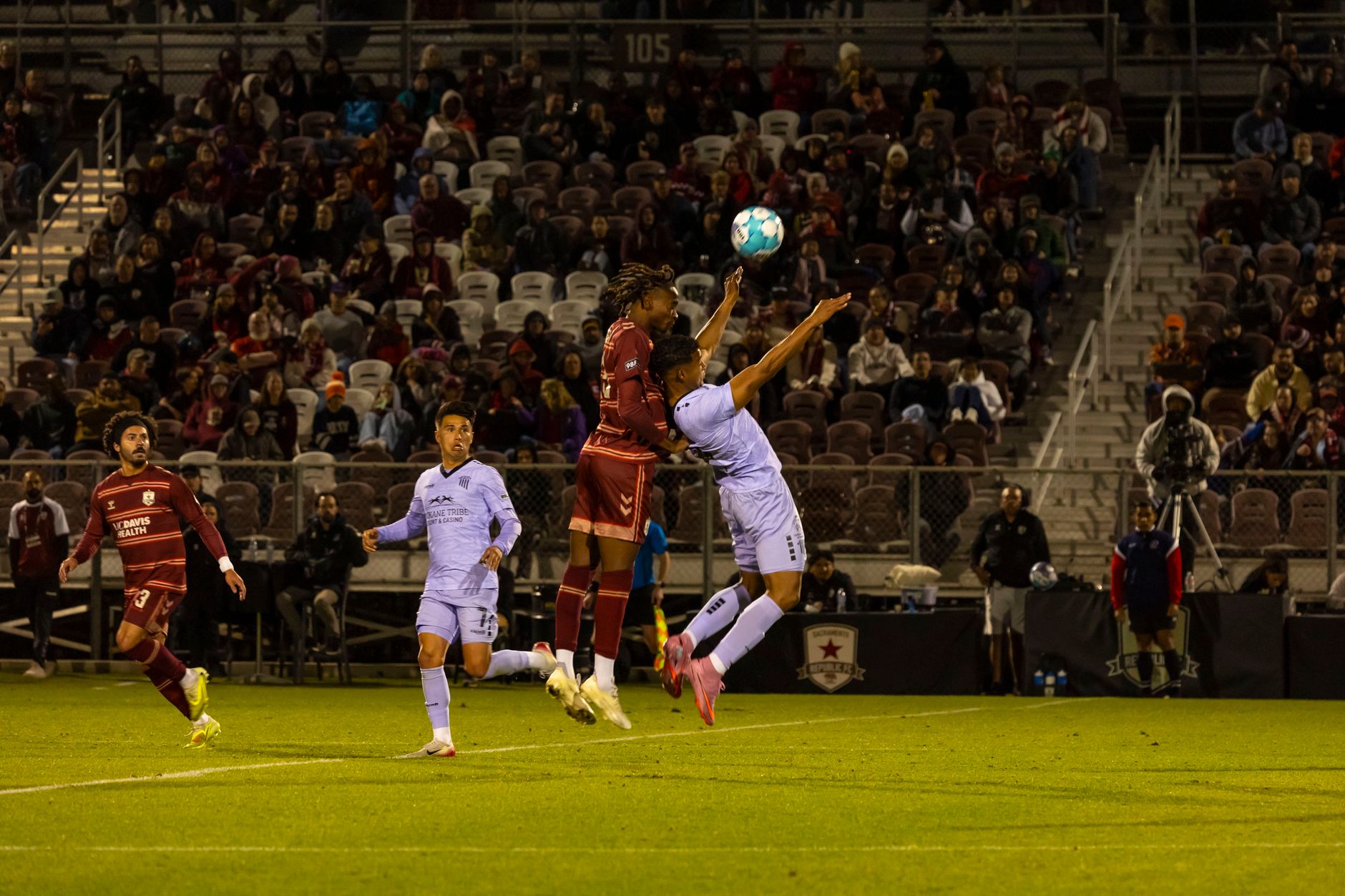 Professional soccer players in action, competing for the ball during a night match at a stadium.
