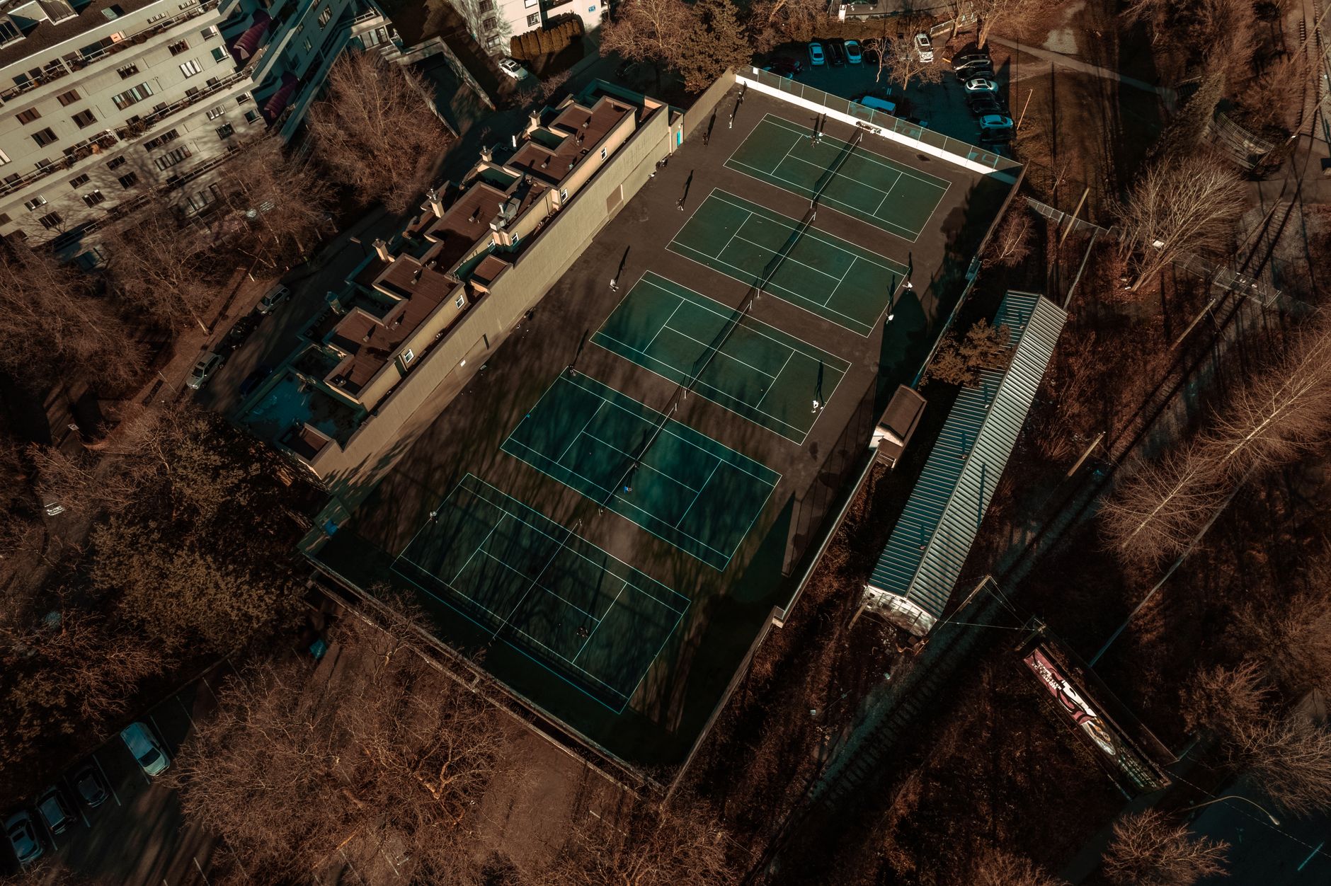 Aerial shot of multiple tennis courts surrounded by bare trees in Vancouver, BC.