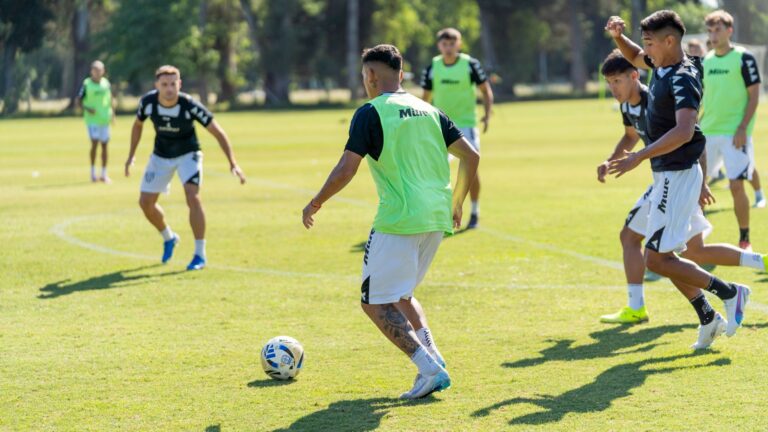 Youth soccer players practicing on the field under bright sunlight, showcasing teamwork and skill.