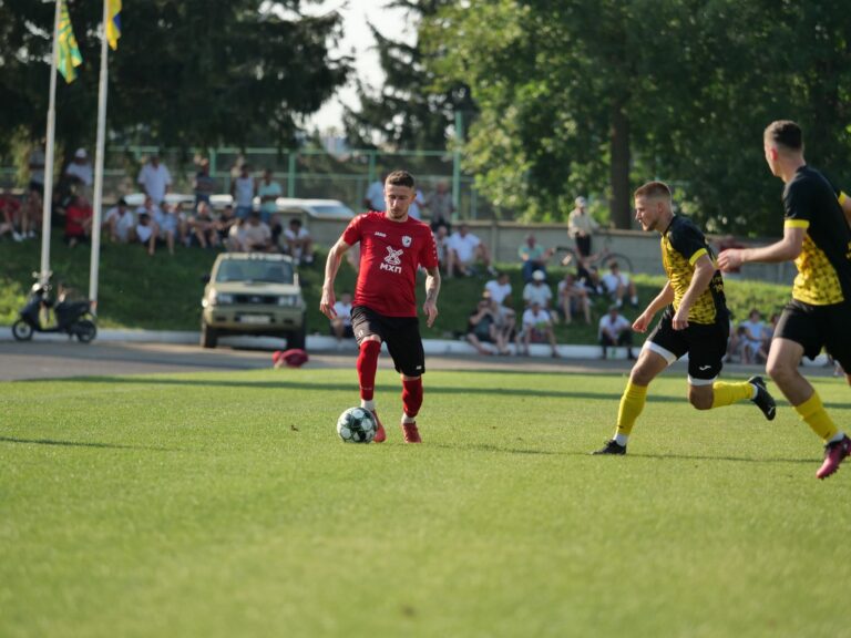 A competitive outdoor soccer match featuring players in dynamic action on a sunny day.