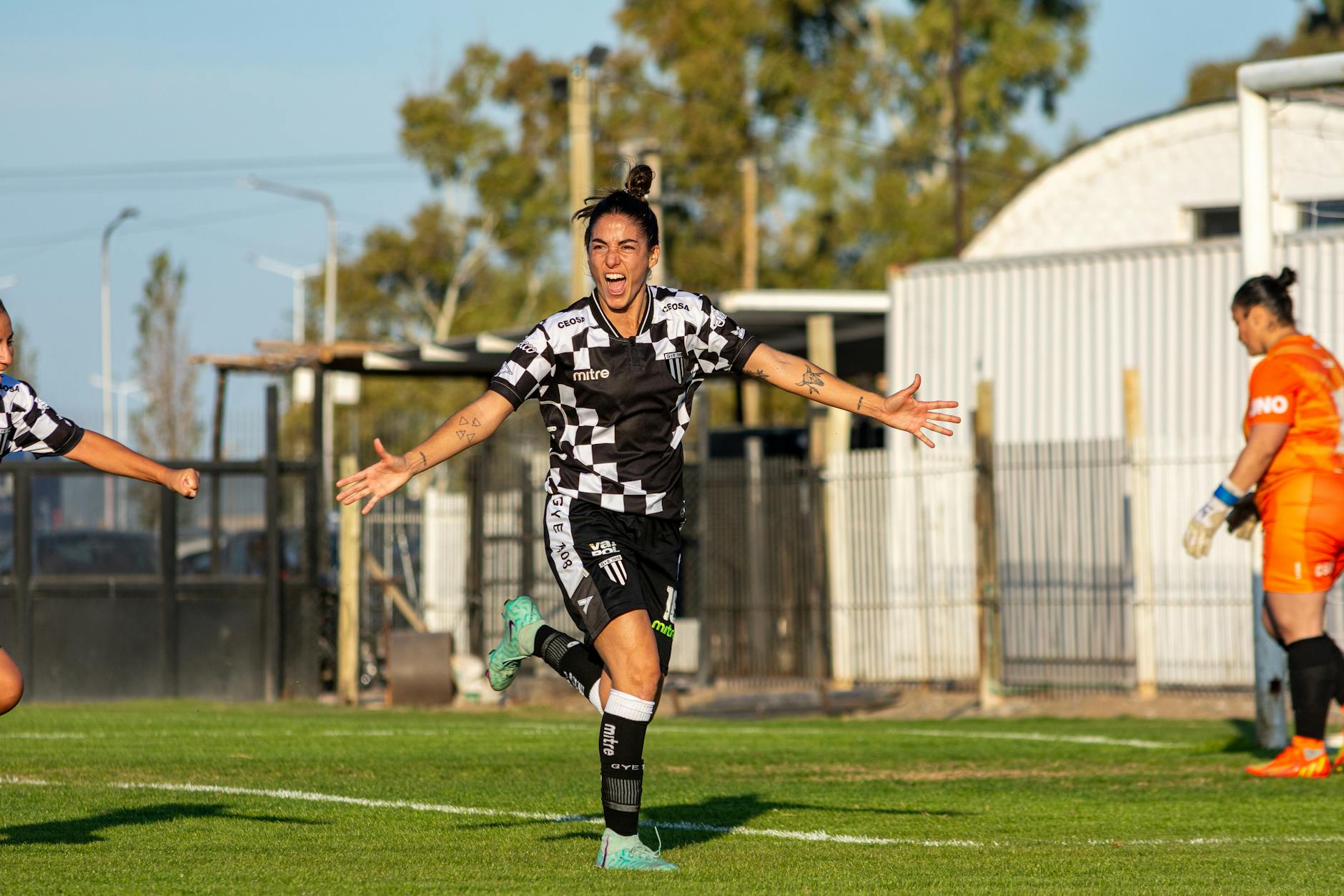 A female soccer player celebrating a goal during an outdoor match.