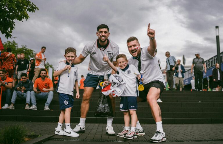 Group of enthusiastic soccer fans celebrating victory outside the stadium on game day.