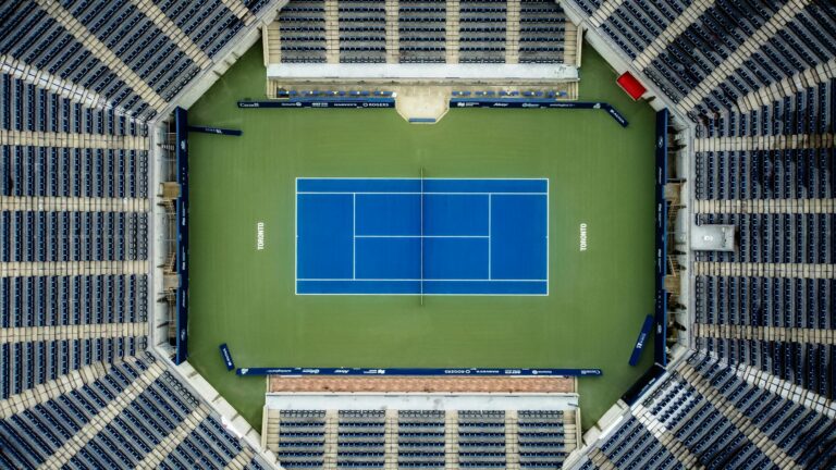 Top-down view of an empty tennis court in a stadium, perfect for sports-themed projects.