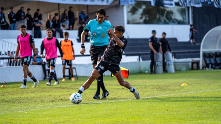 Dynamic soccer game action showing a player in motion and referee nearby.