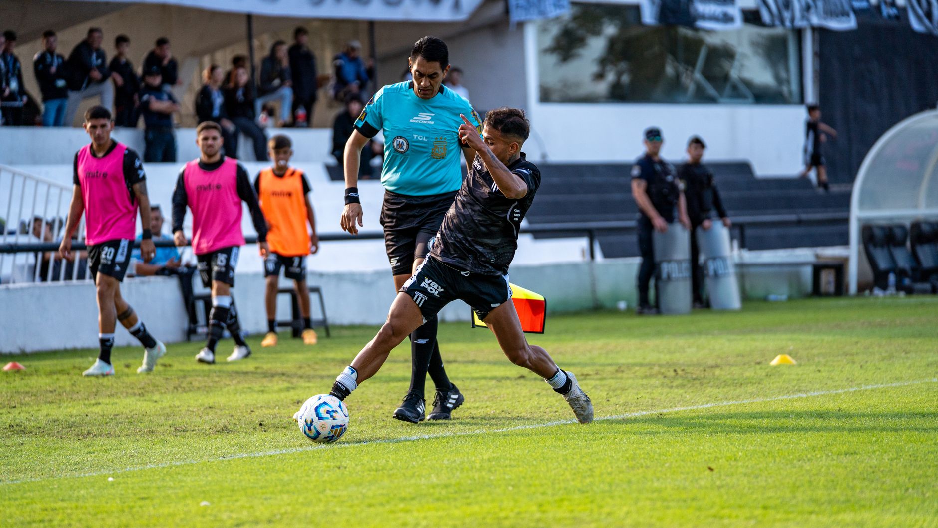 Dynamic soccer game action showing a player in motion and referee nearby.