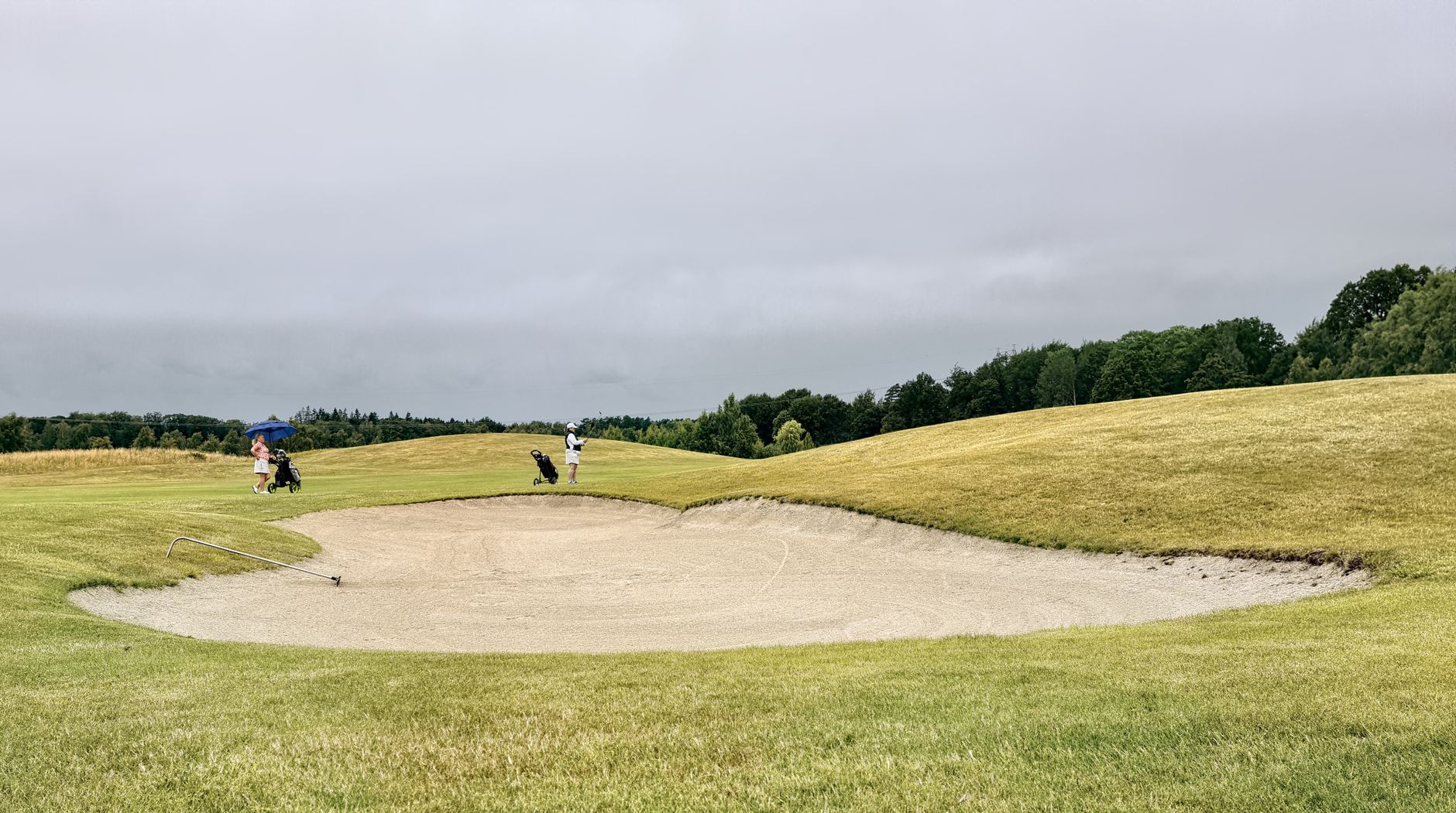 Two golfers on a lush golf course with a sand bunker in Skåne, Sweden.