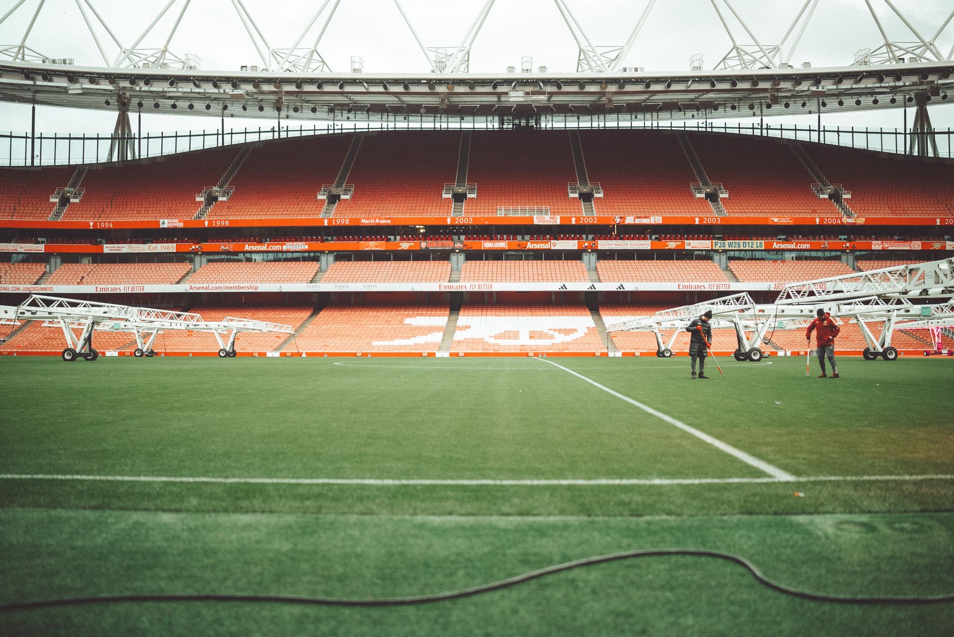 A view of Emirates Stadium in London, featuring the field and maintenance crew.