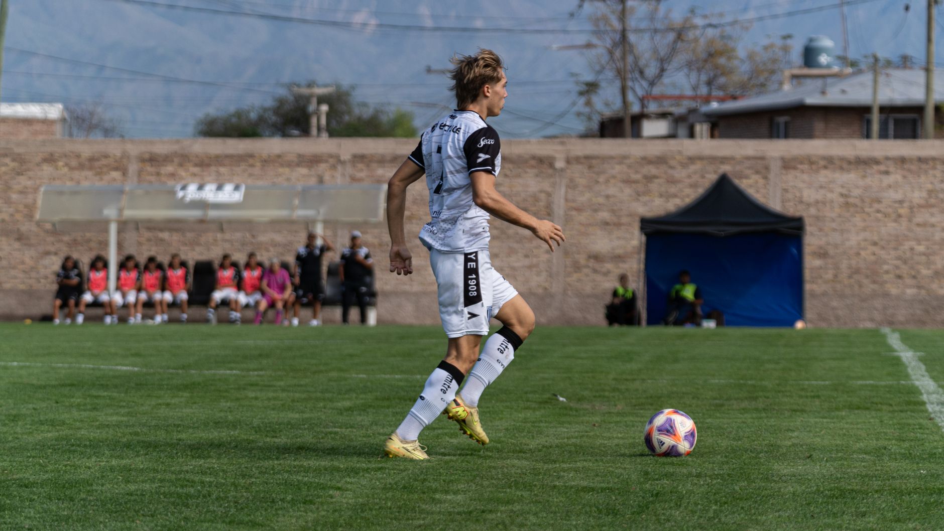 Dynamic soccer match with player in action, showcasing speed and agility on a green field.