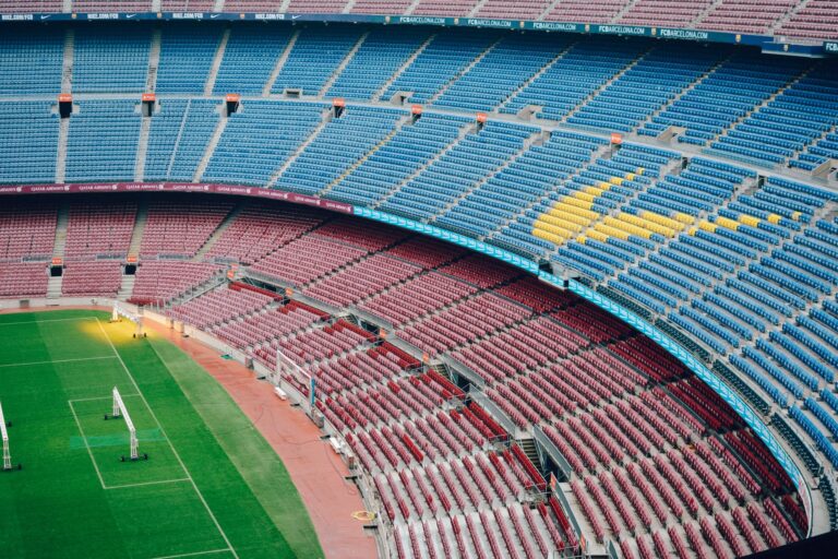 Aerial view of the empty Camp Nou stadium in Barcelona with colorful seats and green field.