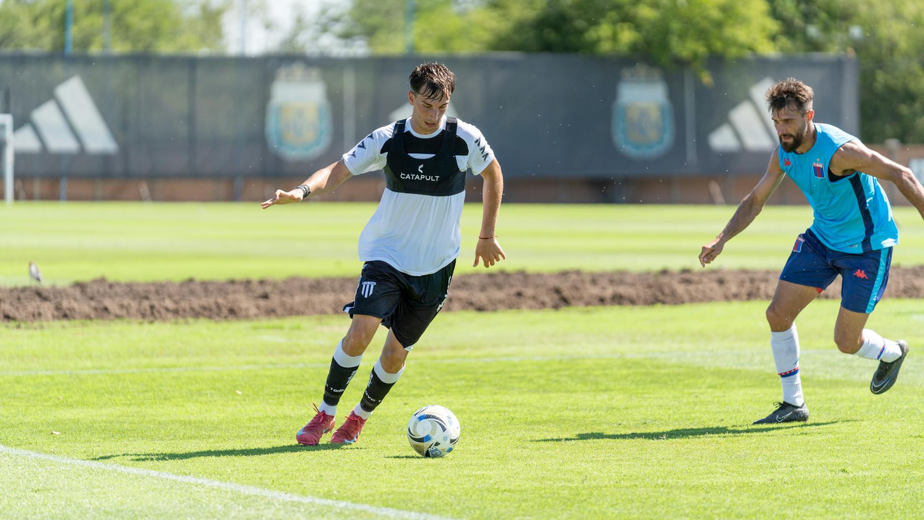 Two soccer players in action on a sunny day during an outdoor match.