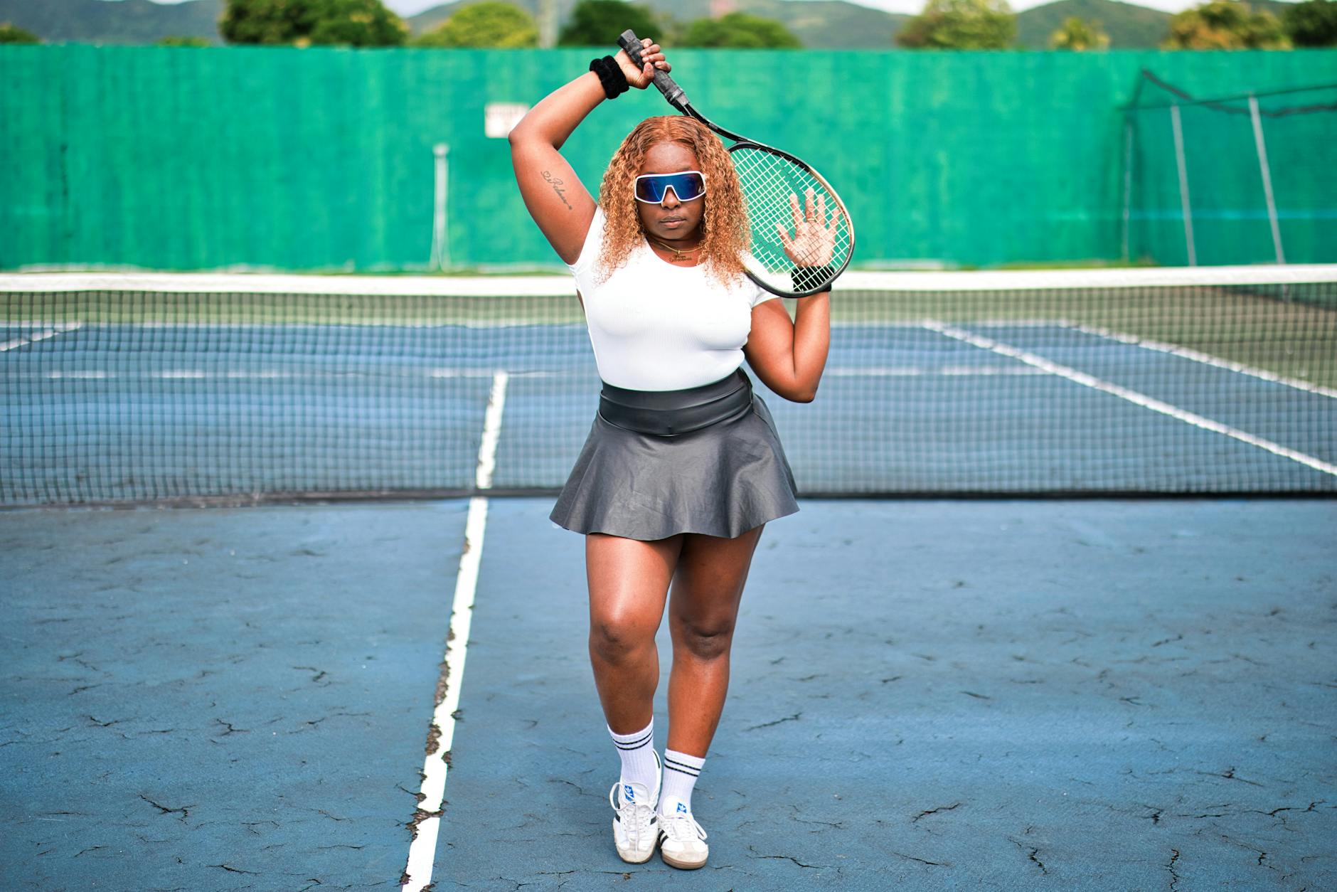 Female tennis player poses confidently with a racket on an outdoor court in Saint Kitts.