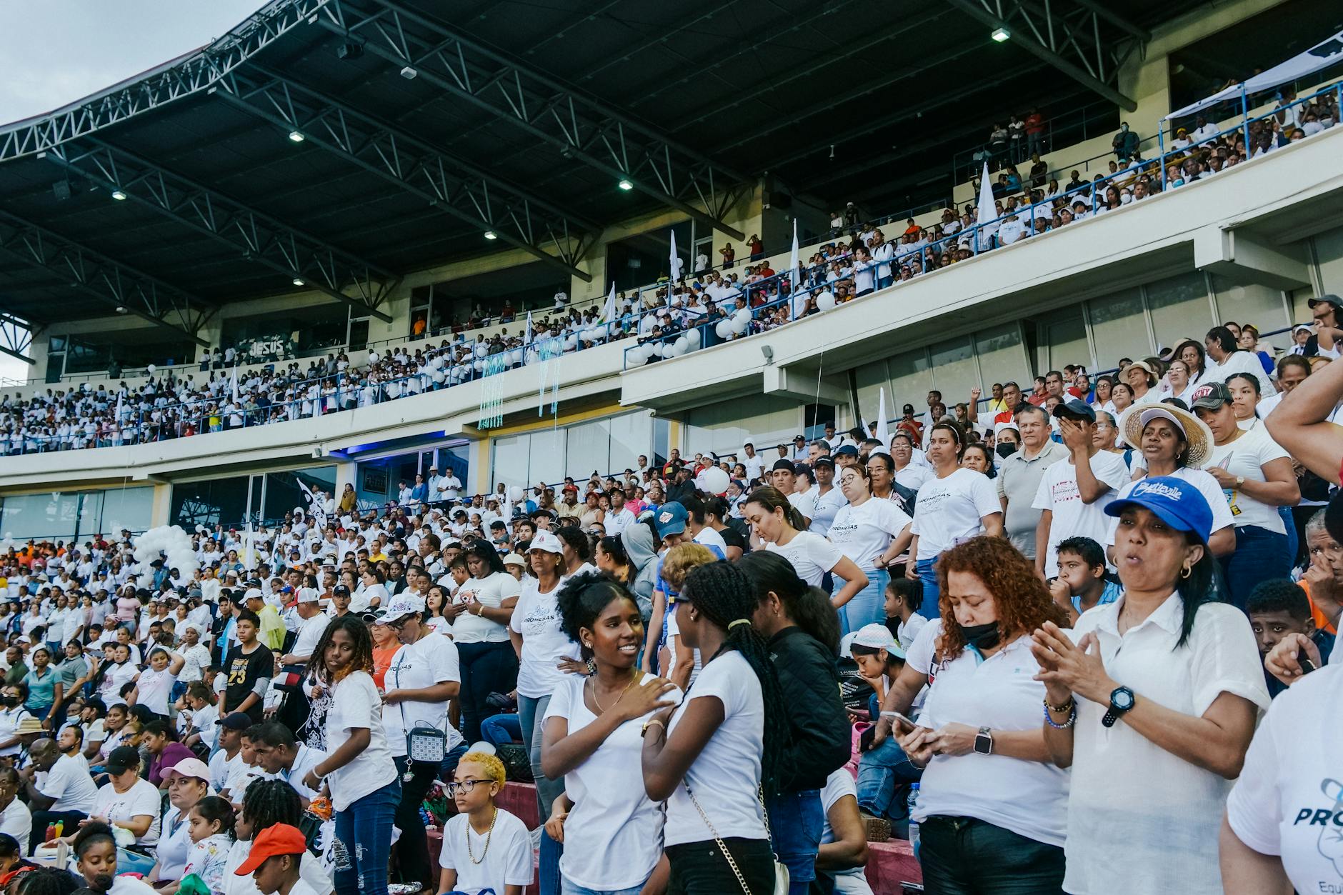 A vibrant crowd gathers in a stadium, enjoying an exciting event under a covered roof.