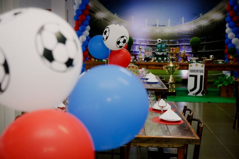 Colorful football party setup indoors with balloons and table settings, perfect for sports enthusiasts.