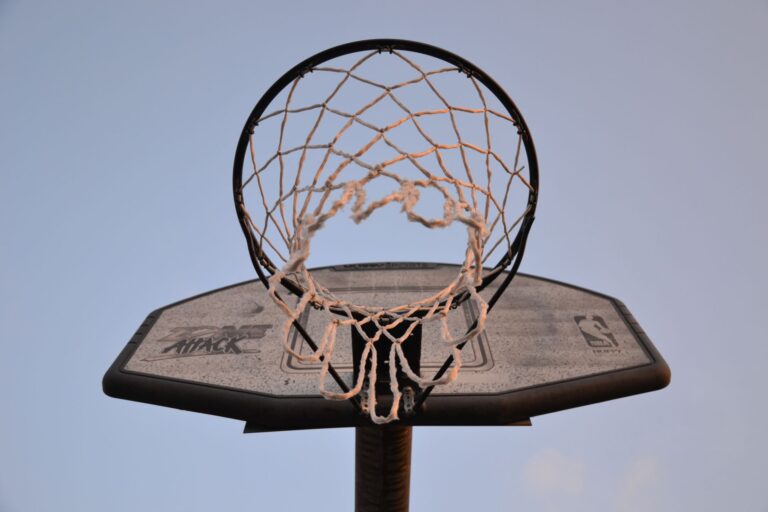 Close-up view of a basketball hoop and net against a clear sky, ideal for sports and leisure themes.