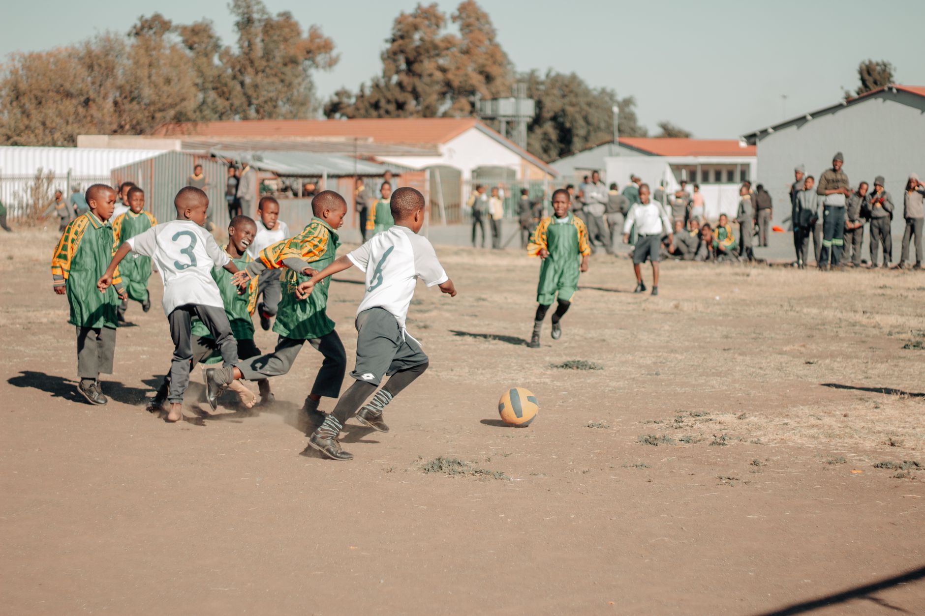 Children engaged in a lively soccer game on a sunny day in South Africa.