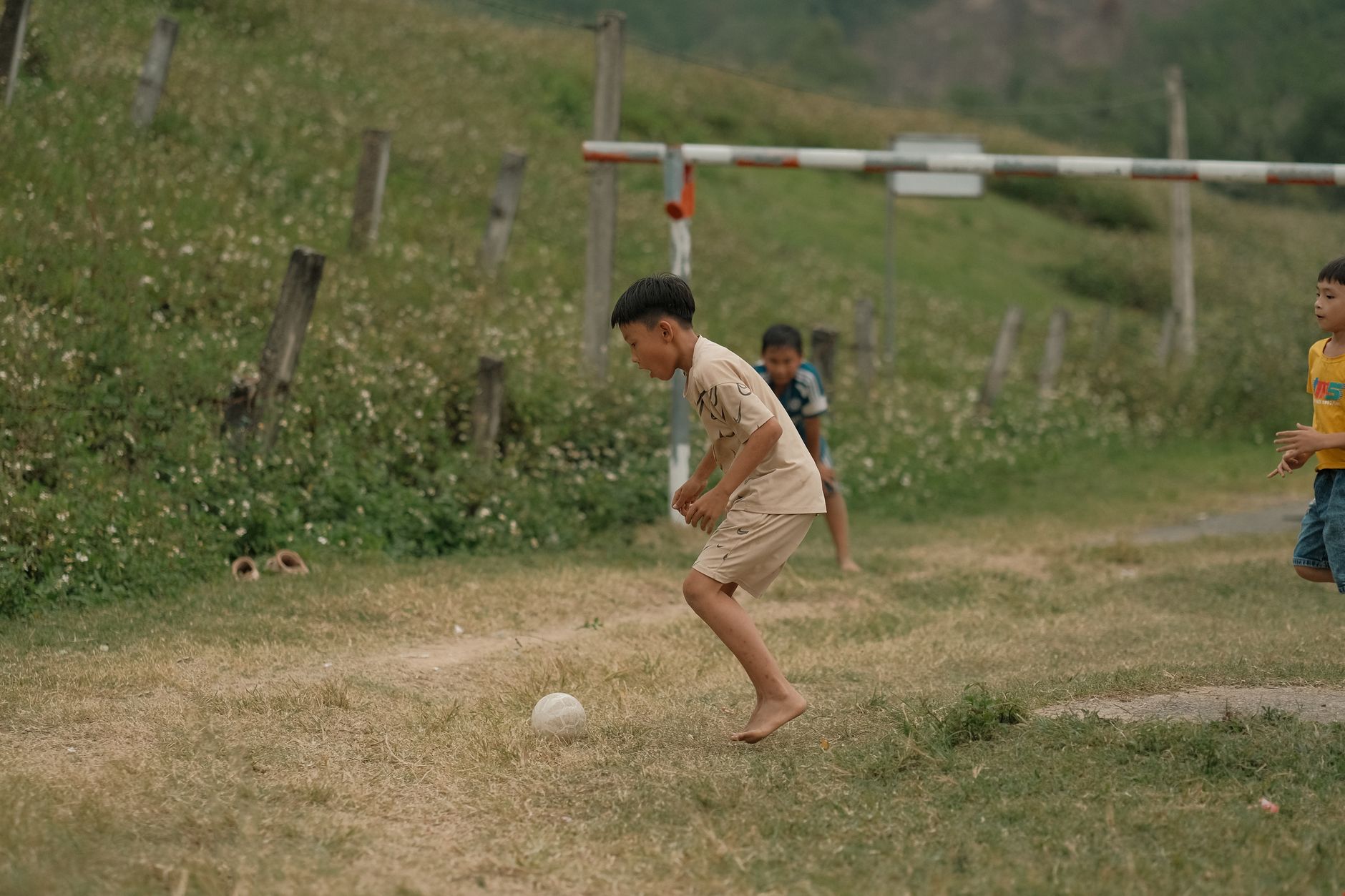 Young boys enjoying a game of soccer on a rural grassy field.