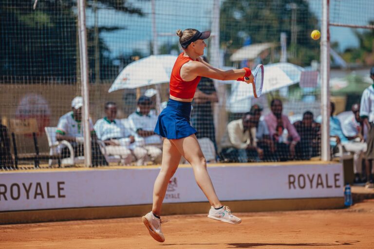 Tennis player in mid-air volley during a competitive outdoor match.