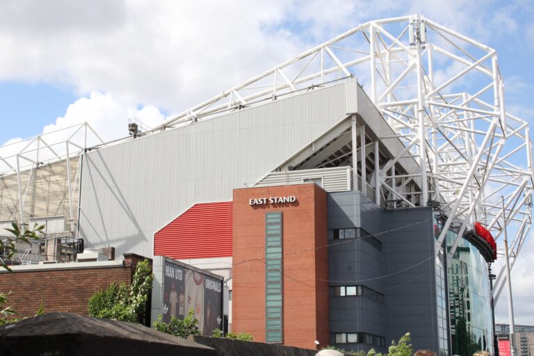 Exterior view of the East Stand at Old Trafford Stadium on a sunny day.