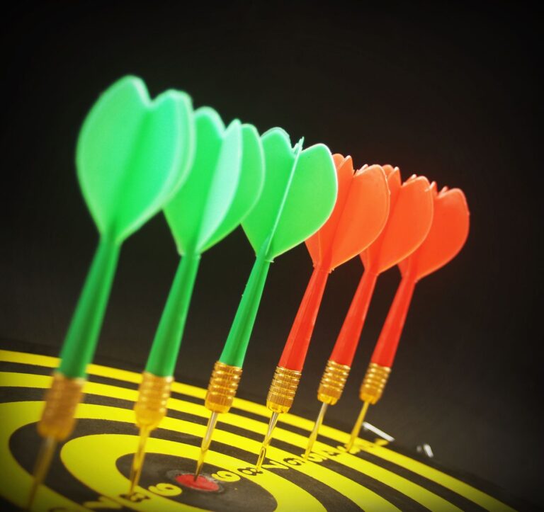 Close-up of colorful darts perfectly aligned on a dartboard target.