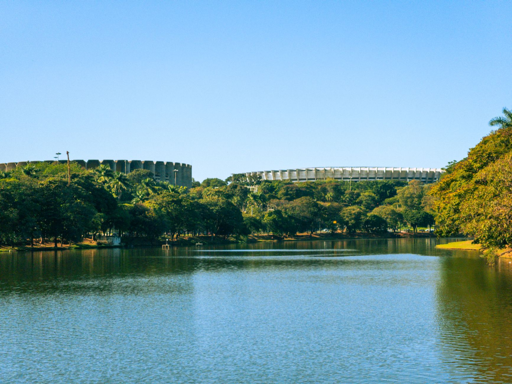 A peaceful view of Pampulha Lagoon with trees and the Mineirão Stadium in Belo Horizonte, Brazil.