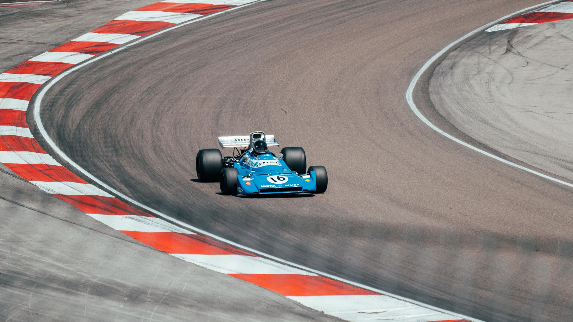 Vintage blue race car speeding on a winding track in Prenois, France.