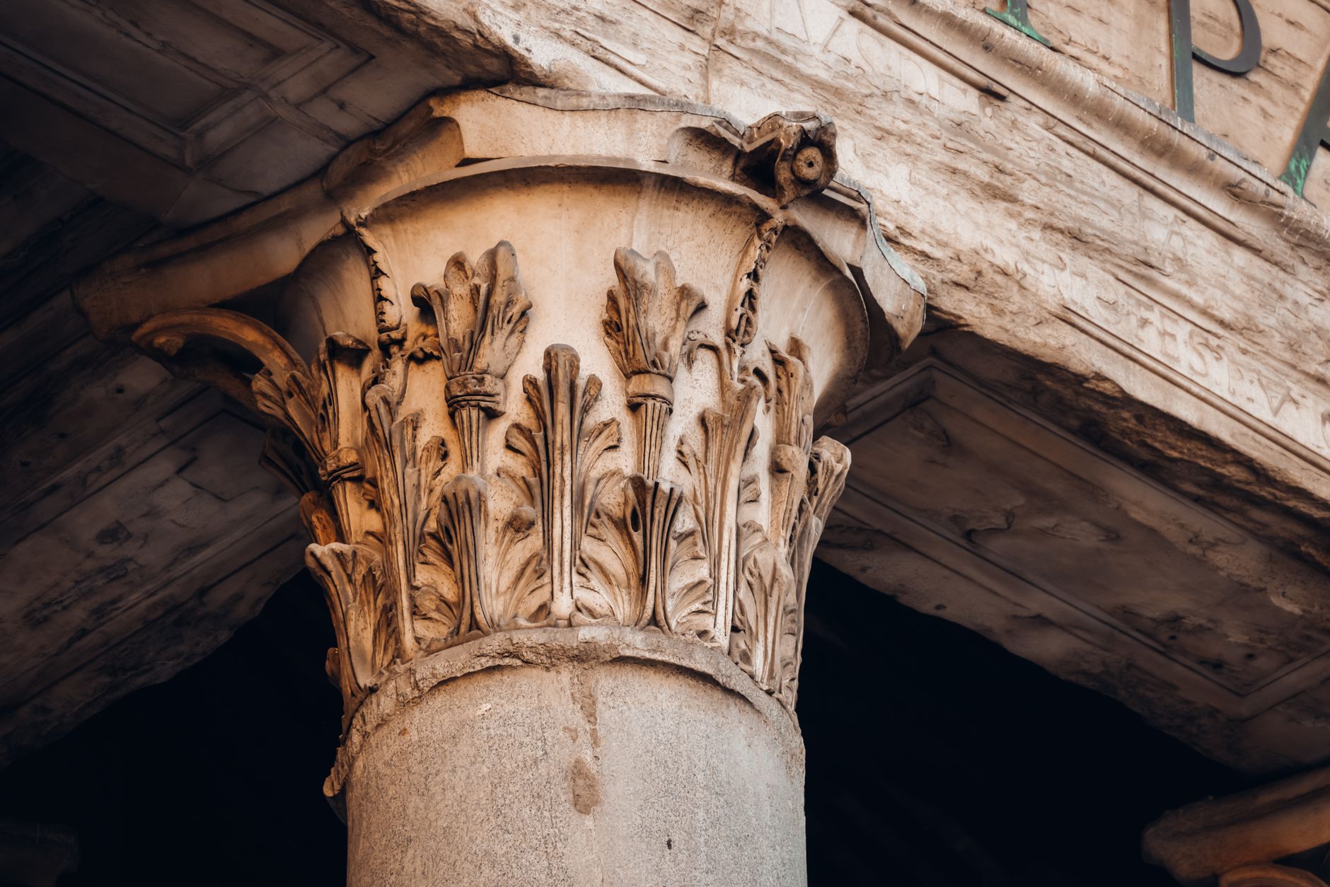 Close-up of a Corinthian column capital showcasing intricate carvings in an ancient architecture setting.
