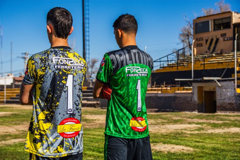 Two young soccer players in colorful jerseys, ready for a match on an urban field.