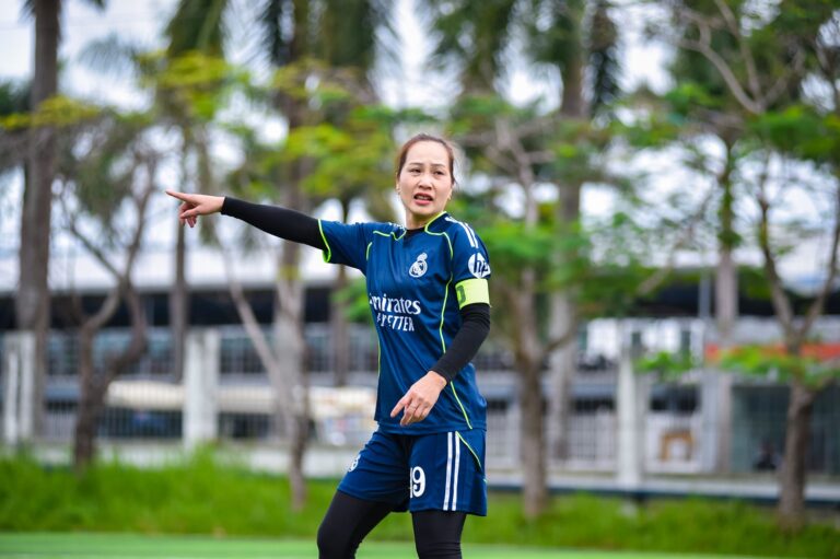 A focused female football player giving directions on a field in Hanoi, Vietnam.