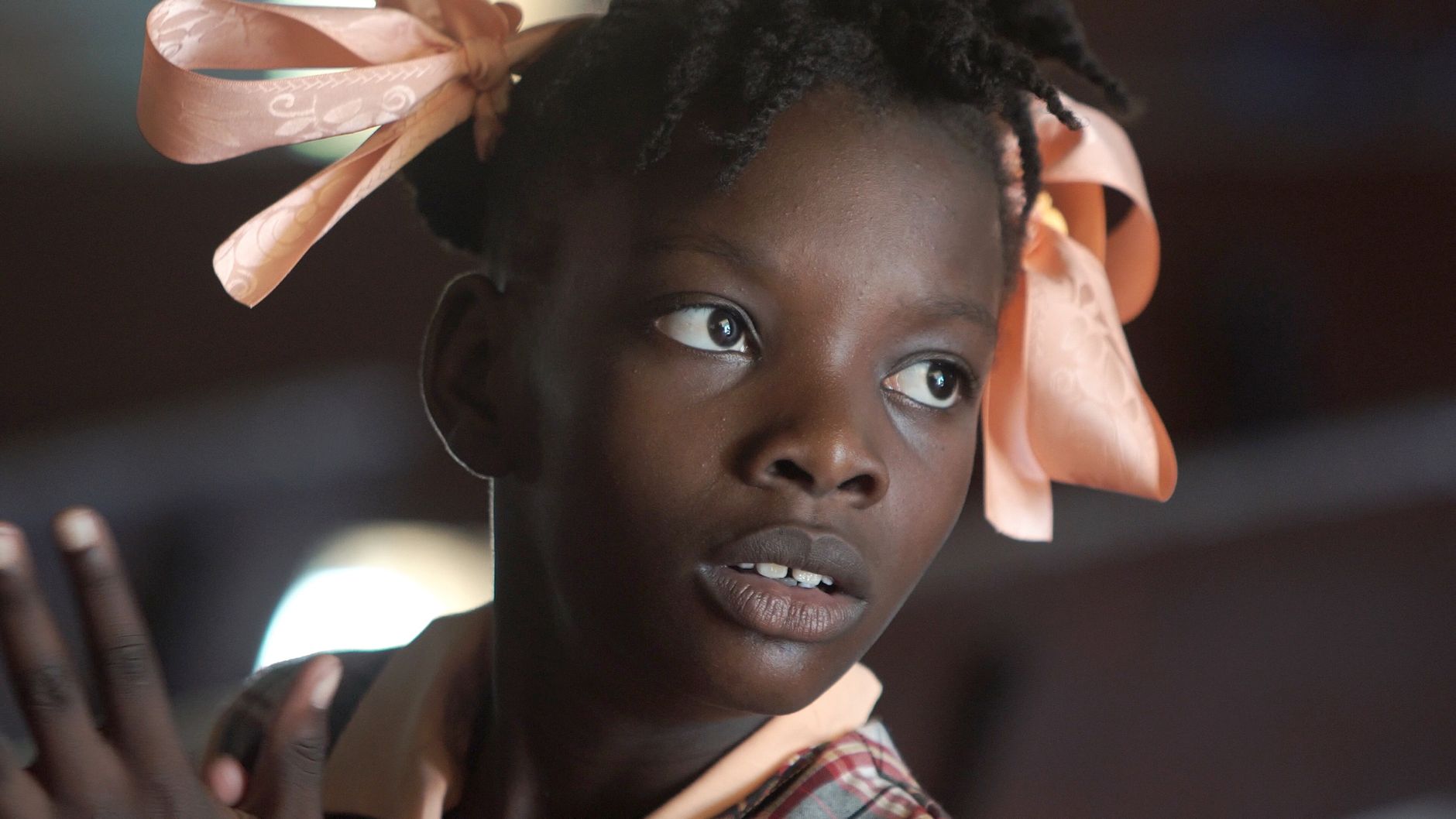 Charming portrait of a young girl in Haiti, showcasing cultural hairstyle with pink bows.