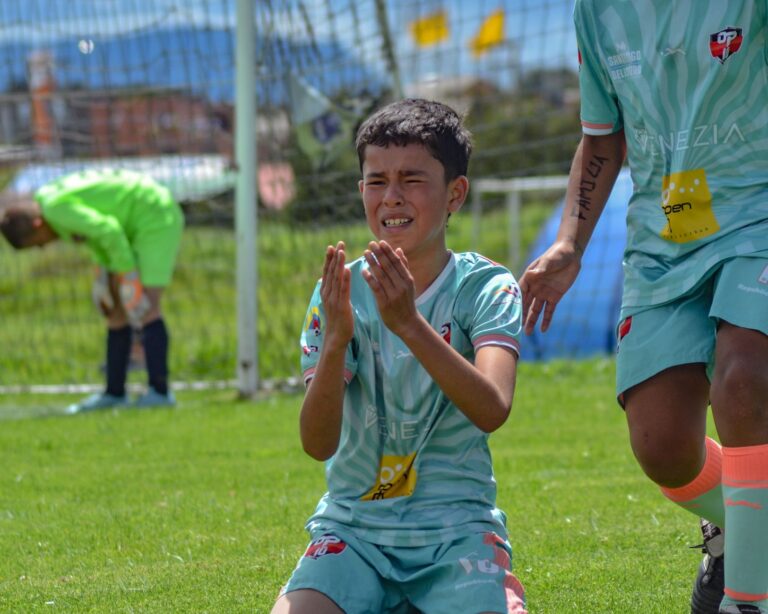 Young soccer player shows emotion after intense play on outdoor field.