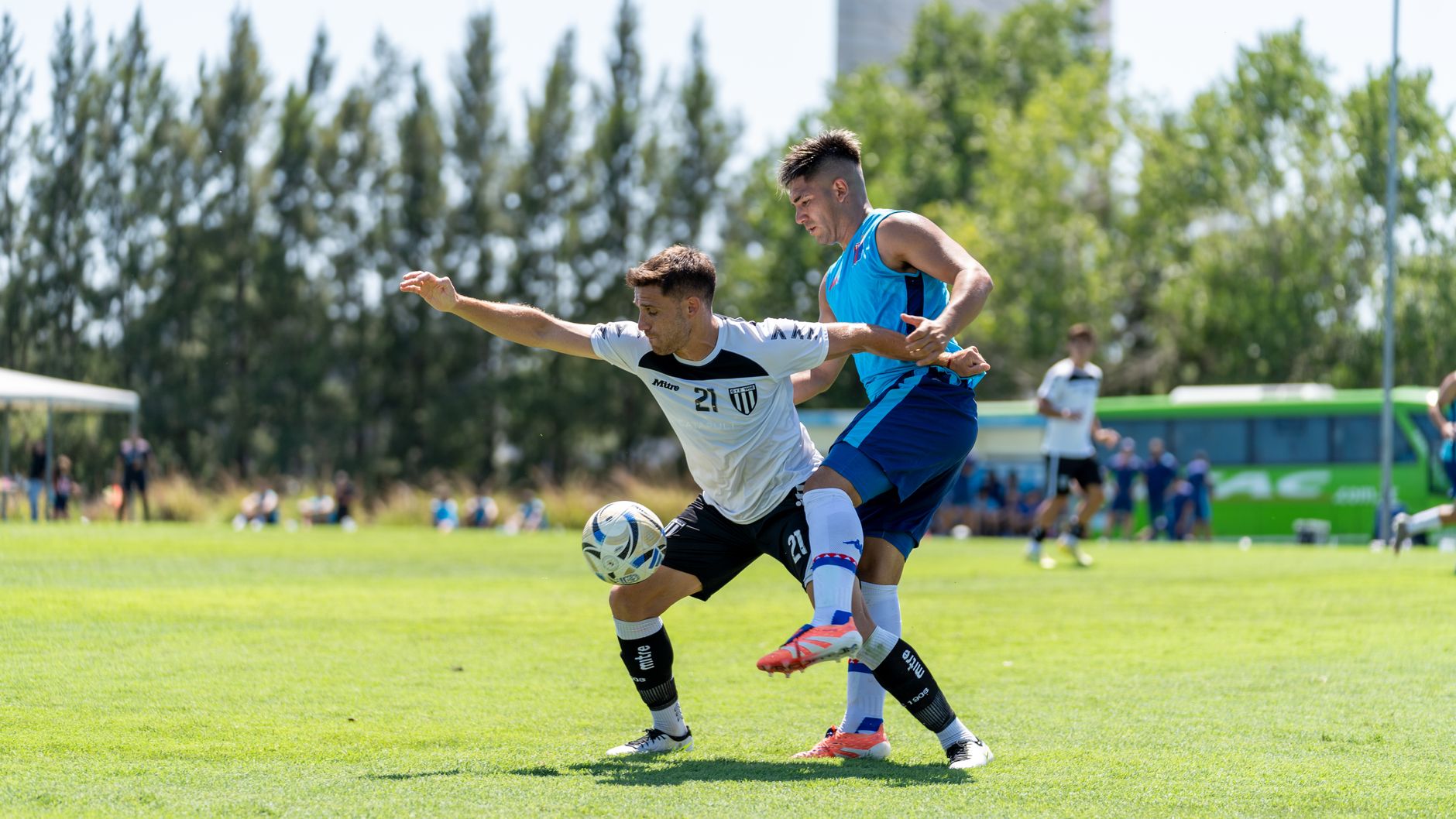 Two soccer players compete fiercely for the ball during an outdoor match.