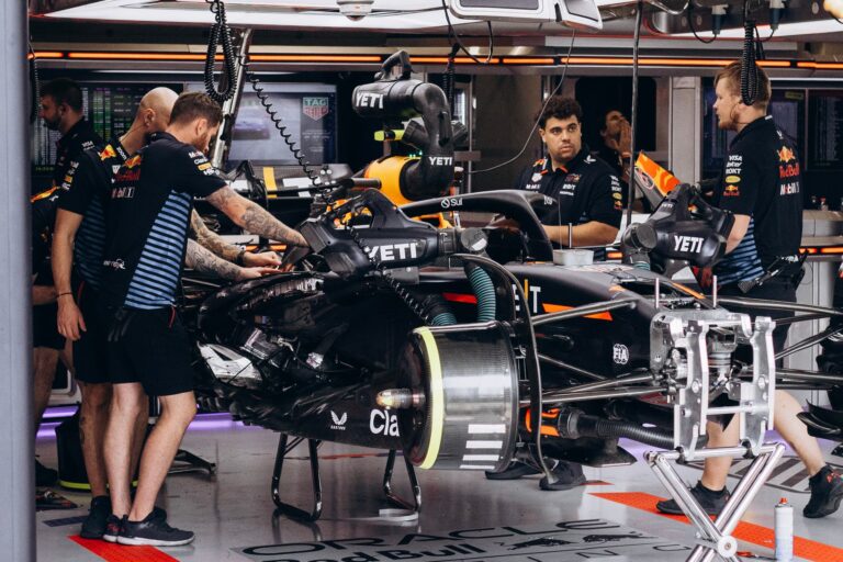 Formula 1 team mechanics work on a race car in the garage, preparing for the competition.