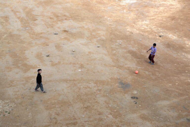 Two children playing soccer on a dirt field in Sefrou, Morocco.