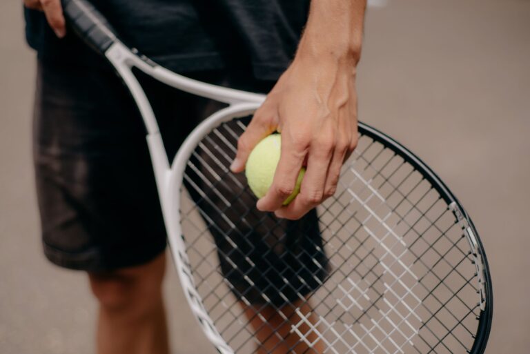 Detailed view of a tennis player holding a tennis ball and racket, preparing for a serve.