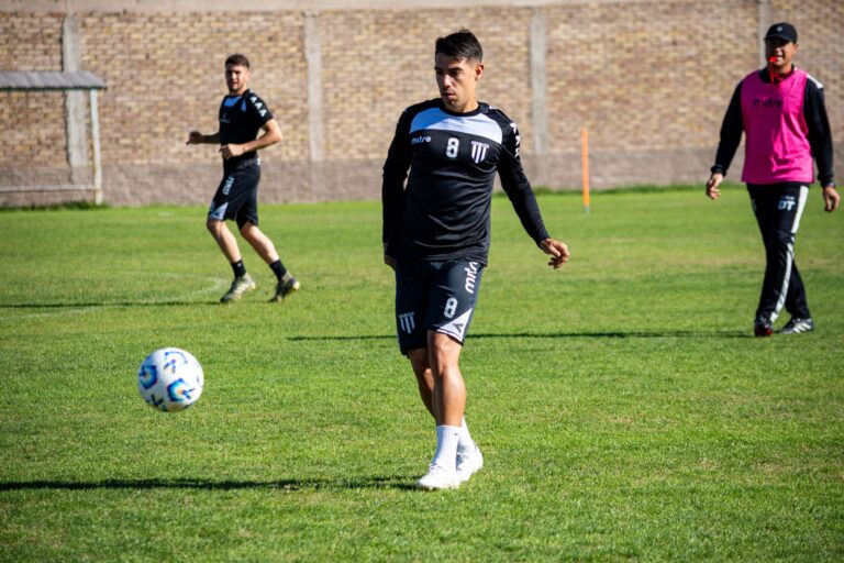 Focused football player in training session on green field under daylight.