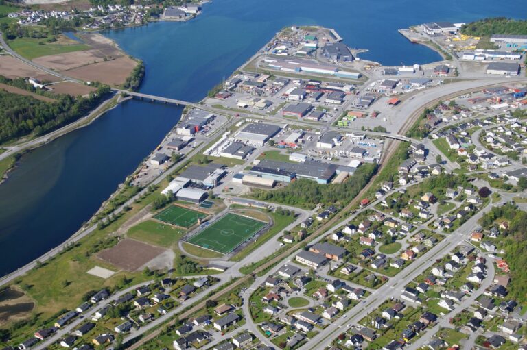 Aerial photo of Åndalsnes, featuring a river, residential area, sports fields, and industrial sector.