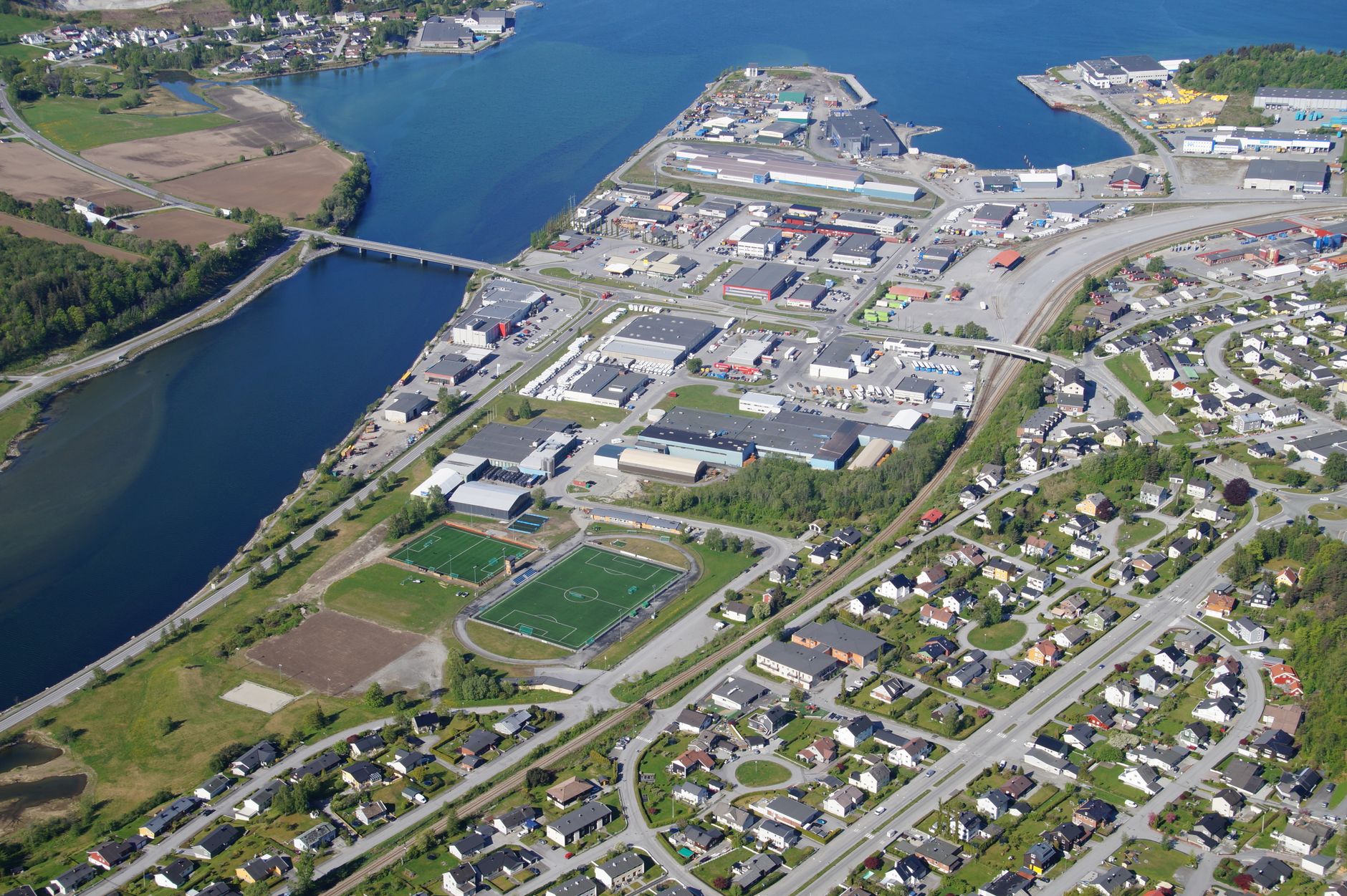 Aerial photo of Åndalsnes, featuring a river, residential area, sports fields, and industrial sector.