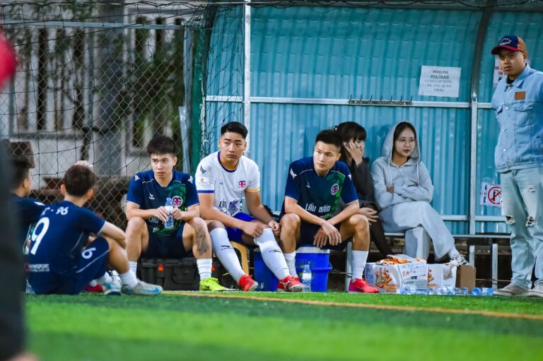 Football team and fans sitting on benches during a break in a local match in Hà Nội, Việt Nam.