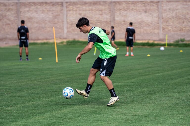 A young male soccer player performing dribbling drills on an outdoor field during daytime practice.