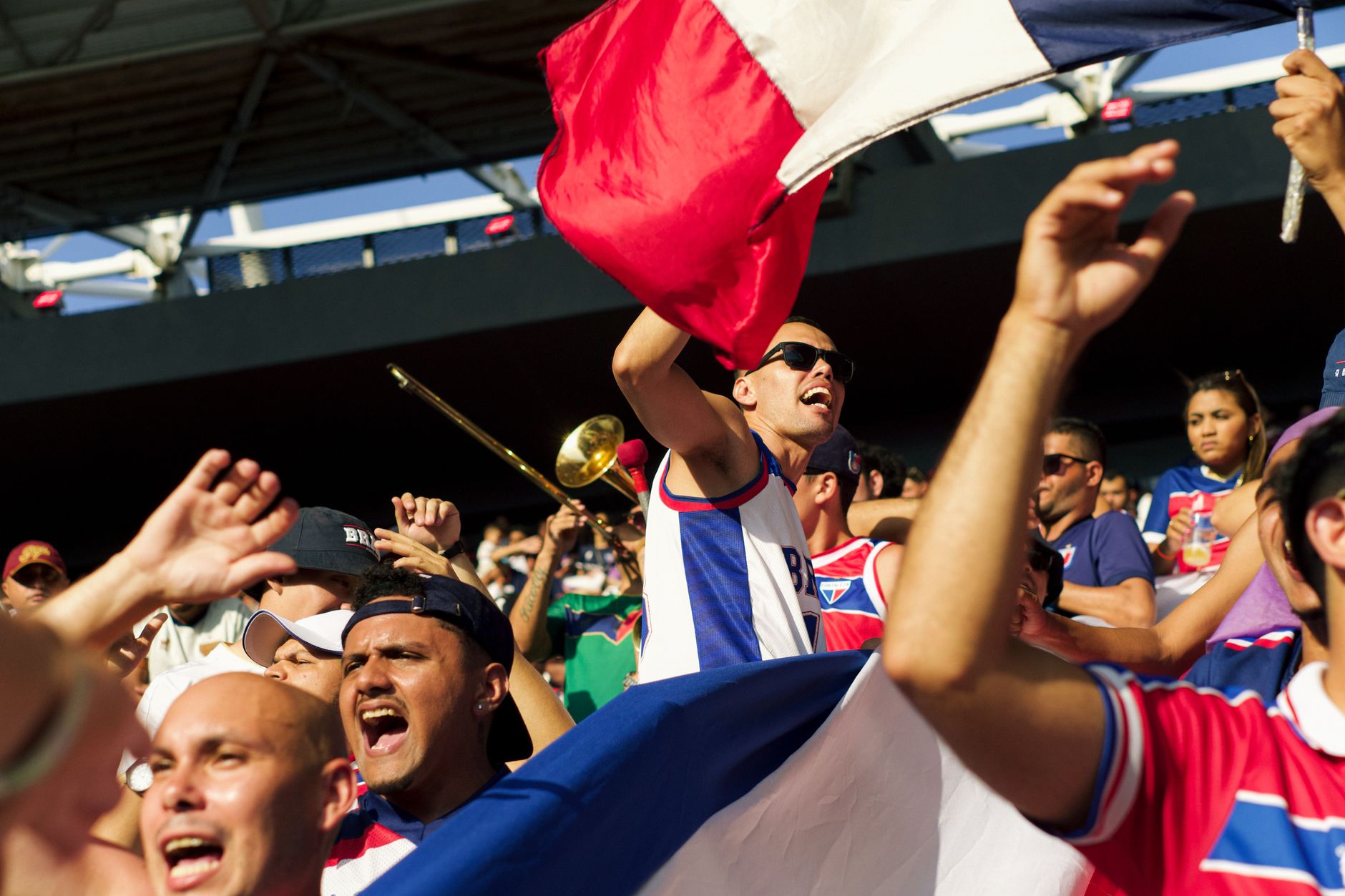 A lively group of soccer fans celebrating energetically with flags and cheering in a stadium.