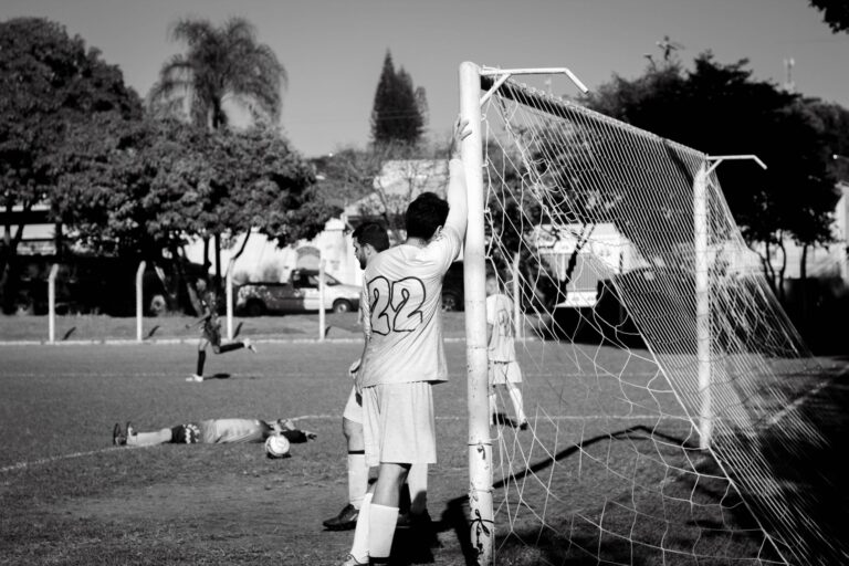 A candid black and white photo capturing players during a soccer match in Itapira, Brazil.