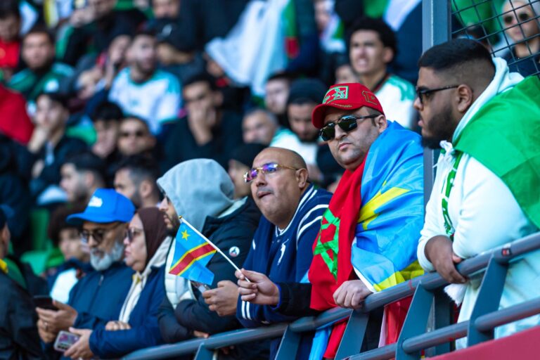 A lively crowd of multi-cultural fans supports their team at a football stadium.