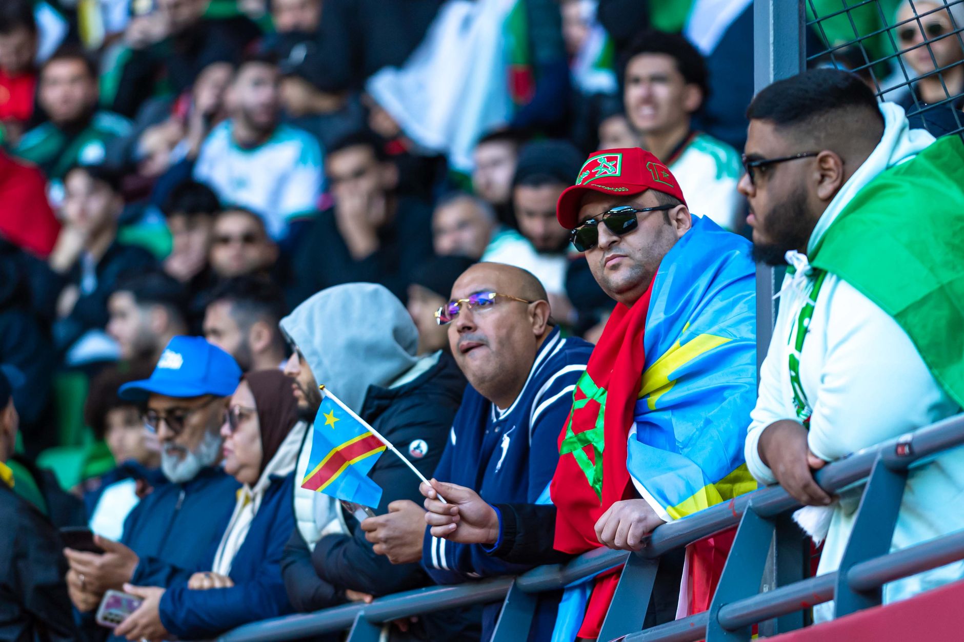 A lively crowd of multi-cultural fans supports their team at a football stadium.