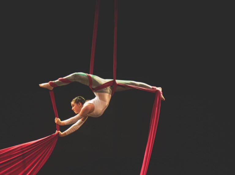 Aerial silk performer showcasing graceful acrobatics on vibrant red silks.