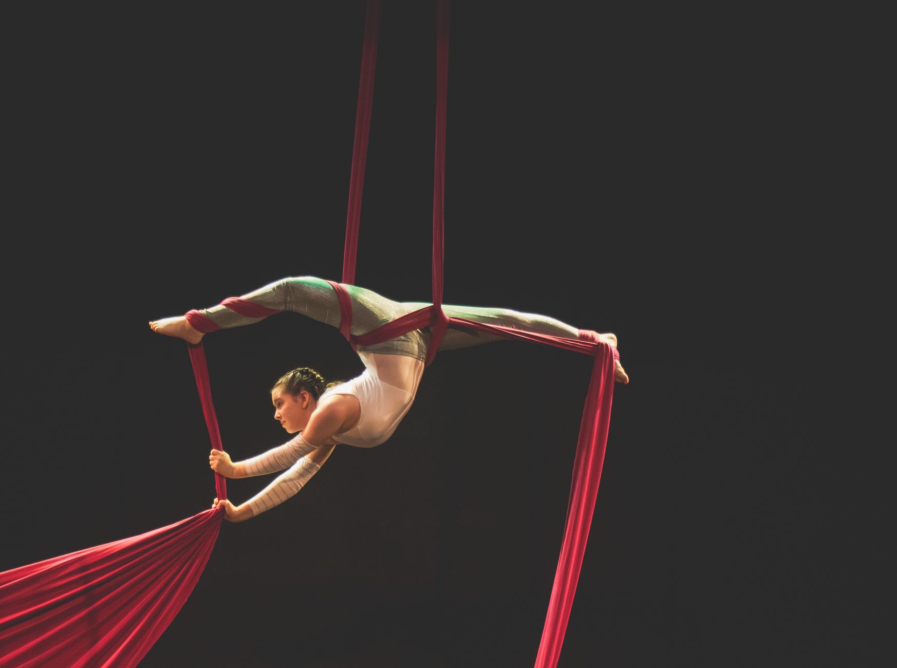 Aerial silk performer showcasing graceful acrobatics on vibrant red silks.