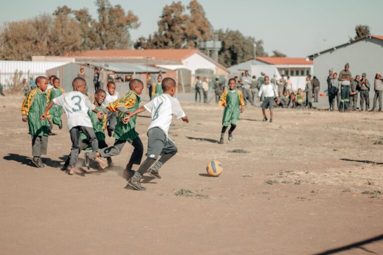 Children engaged in a lively soccer game on a sunny day in South Africa.