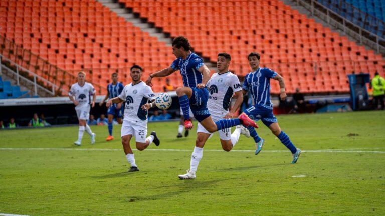 Soccer players competing in a dynamic match on a green field with stadium seating.