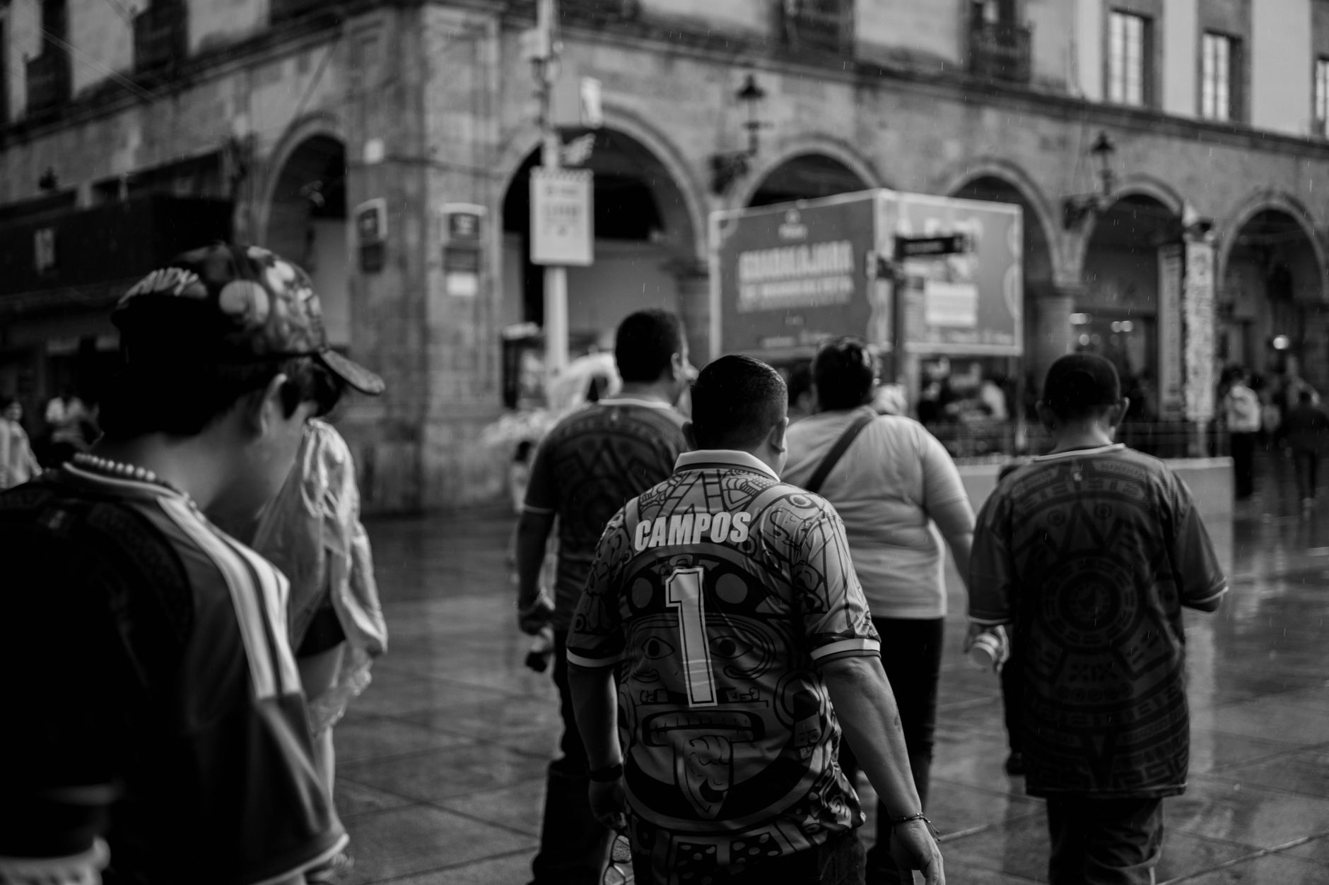 Black and white image of people walking in a historic urban area.